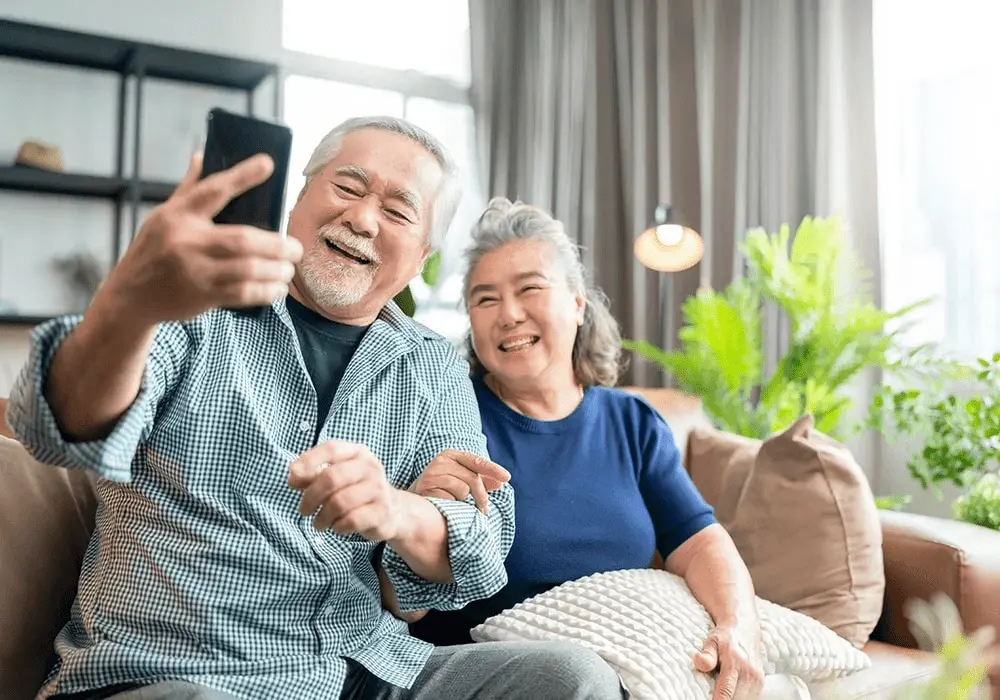 An elderly couple smiling and taking a selfie together